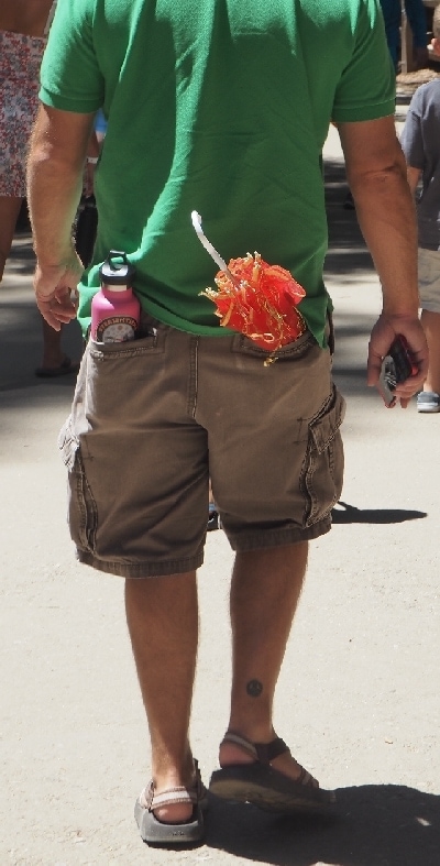 Auf dem Foto ist ein Mann zu sehen, der eine pinkfarbene Kindertrinkflasche in der Hosentasche hat