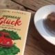 Das Buch "German Glück" liegt im Sonnenschein, ein angebissener Berliner daneben - manchmal reicht das zum Glücklichsein